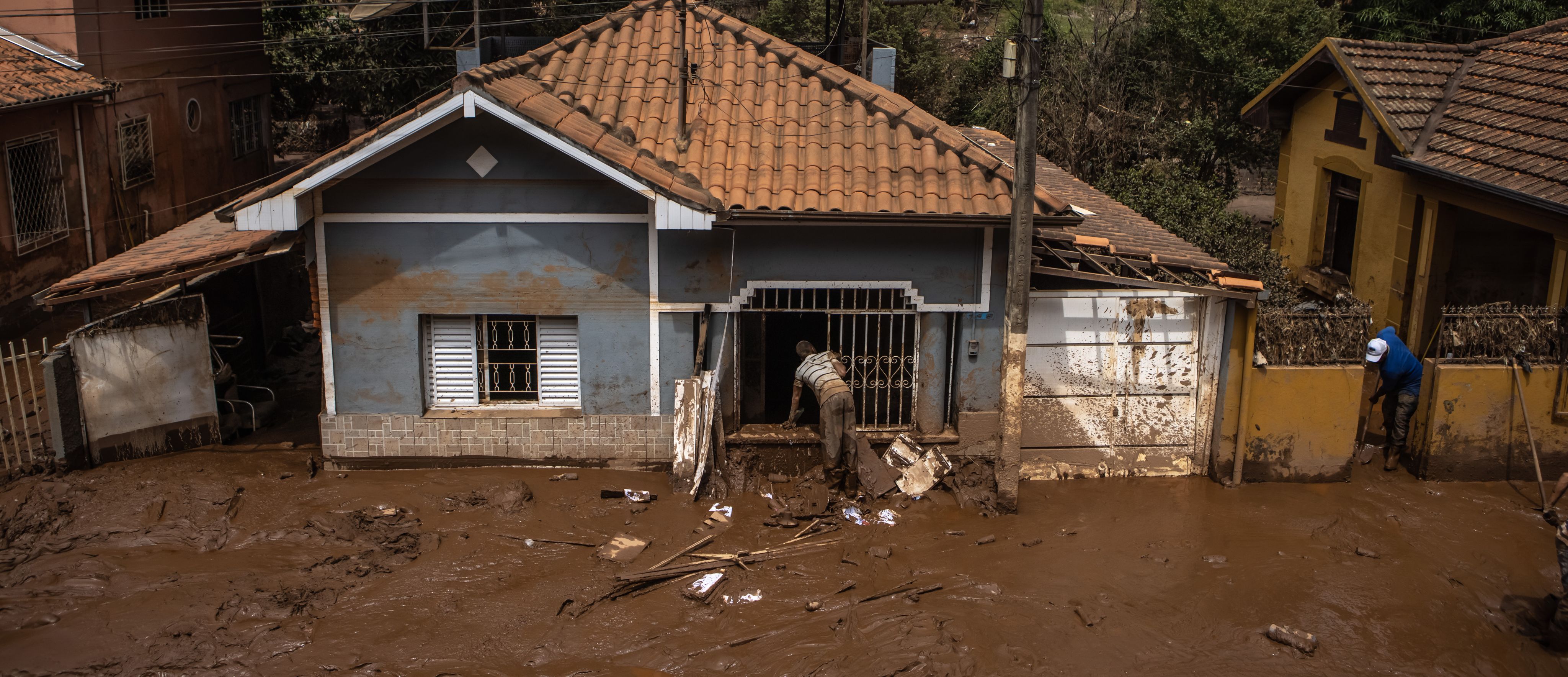 Residents clear mud and debris from homes following heavy rain and flooding in Raposos, Minas Gerais state, Brazil. Heavy downpours in January, even for a wet season, brought flooding that halted iron mining operations across the state. ©Jonne Roriz/Bloomberg via Getty Images